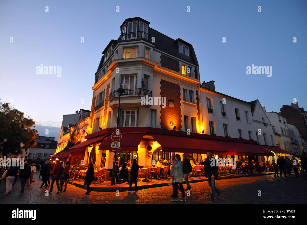 Fußgänger wandern in der Abenddämmerung auf dem Place du Tertre, einem Platz, der von Cafés gesäumt ist und von Straßenkünstlern im Pariser Viertel Montmartre besucht wird. Stockfoto