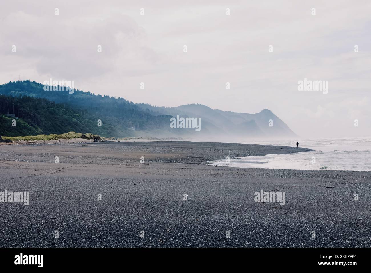 Küste von Oregon an regnerischen Tagen, Sandstrand mit unkennbarer Personenschnur in der Ferne Stockfoto