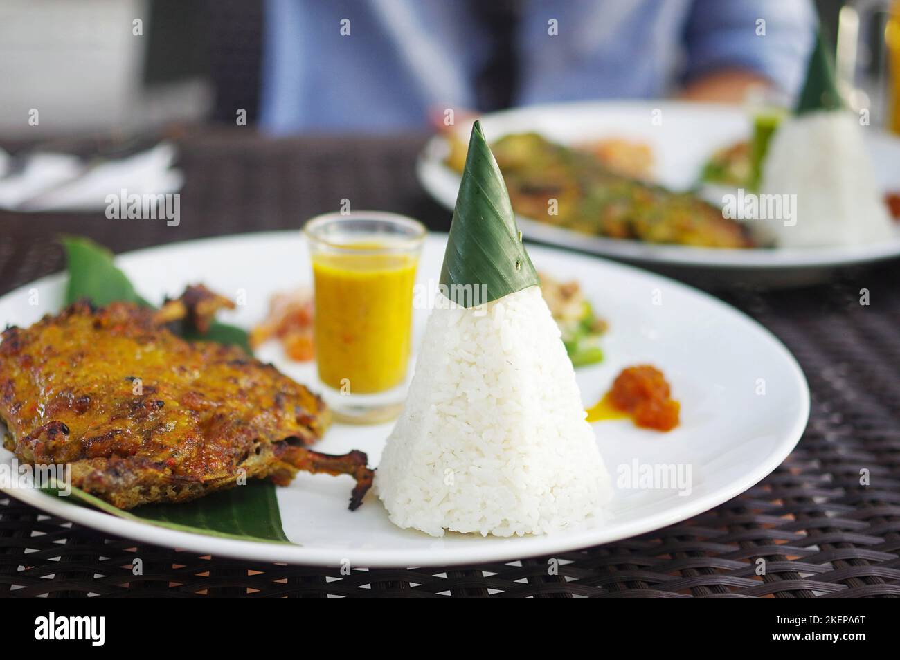 Ein Teller gewürzter karee-gerösteter Ente mit Reiskegel, Sambal und sautiertem Gemüse in einem modernen balinesischen Restaurant in Seminyak (Kayu Aya), Bali Stockfoto