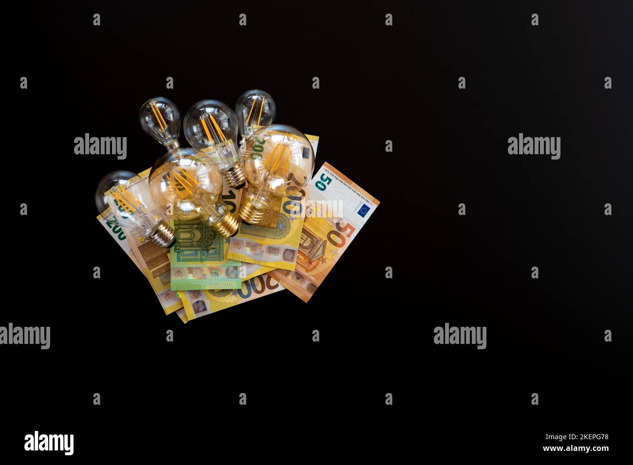 Zahlung der Stromkosten. Strompreis in Europa.Glühbirnen und Euro-Banknoten auf schwarzem Hintergrund.Krise im Energiesektor.Energie Stockfoto