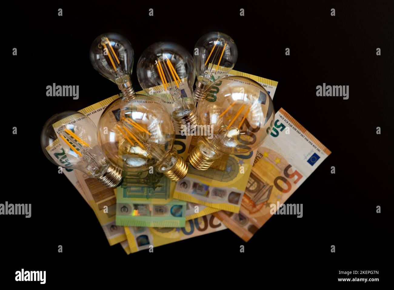 Strompreis in Europa.Glühbirnen und Euro-Banknoten auf schwarzem Hintergrund.Krise im Energiesektor.Energiekrisensymbol Stockfoto