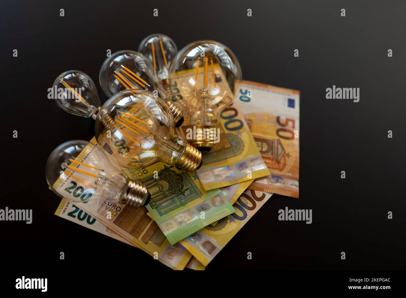 Stromkosten. Strompreis in Europa. Glühbirnen und Euro-Banknoten auf schwarzem Hintergrund. Krise im Energiesektor. Energiekrise Stockfoto