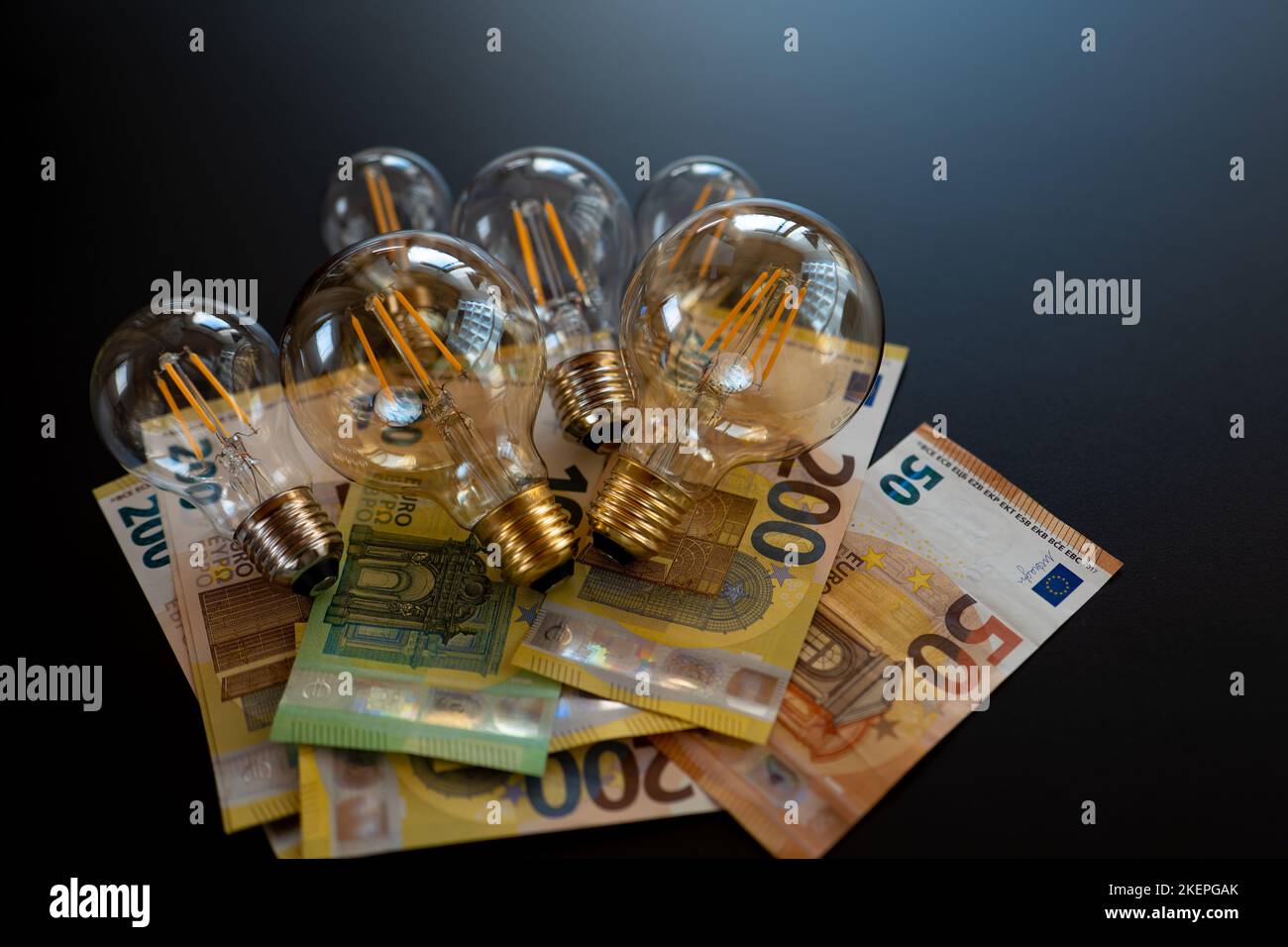 Zahlung der Stromkosten. Strompreis in Europa. Glühbirnen und Euro-Banknoten auf schwarzem Hintergrund. Krise im Energiesektor Stockfoto