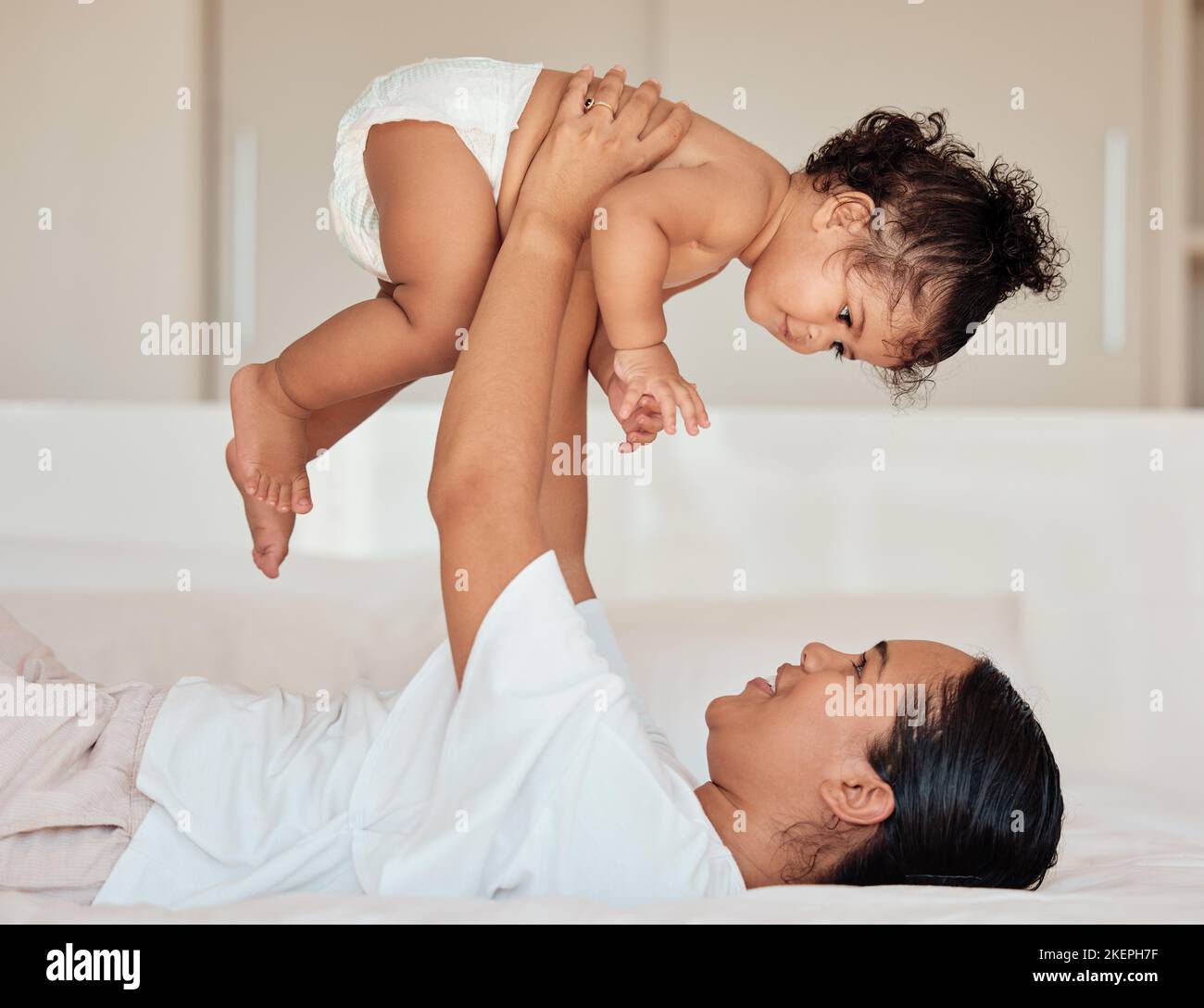 Liebe, Mutter und Baby in der Luft im Schlafzimmer, spielerisch sein und sich zu Hause verbinden. Mama, Kleinkind und Kind spielen auf dem Bett, lieben und Stockfoto