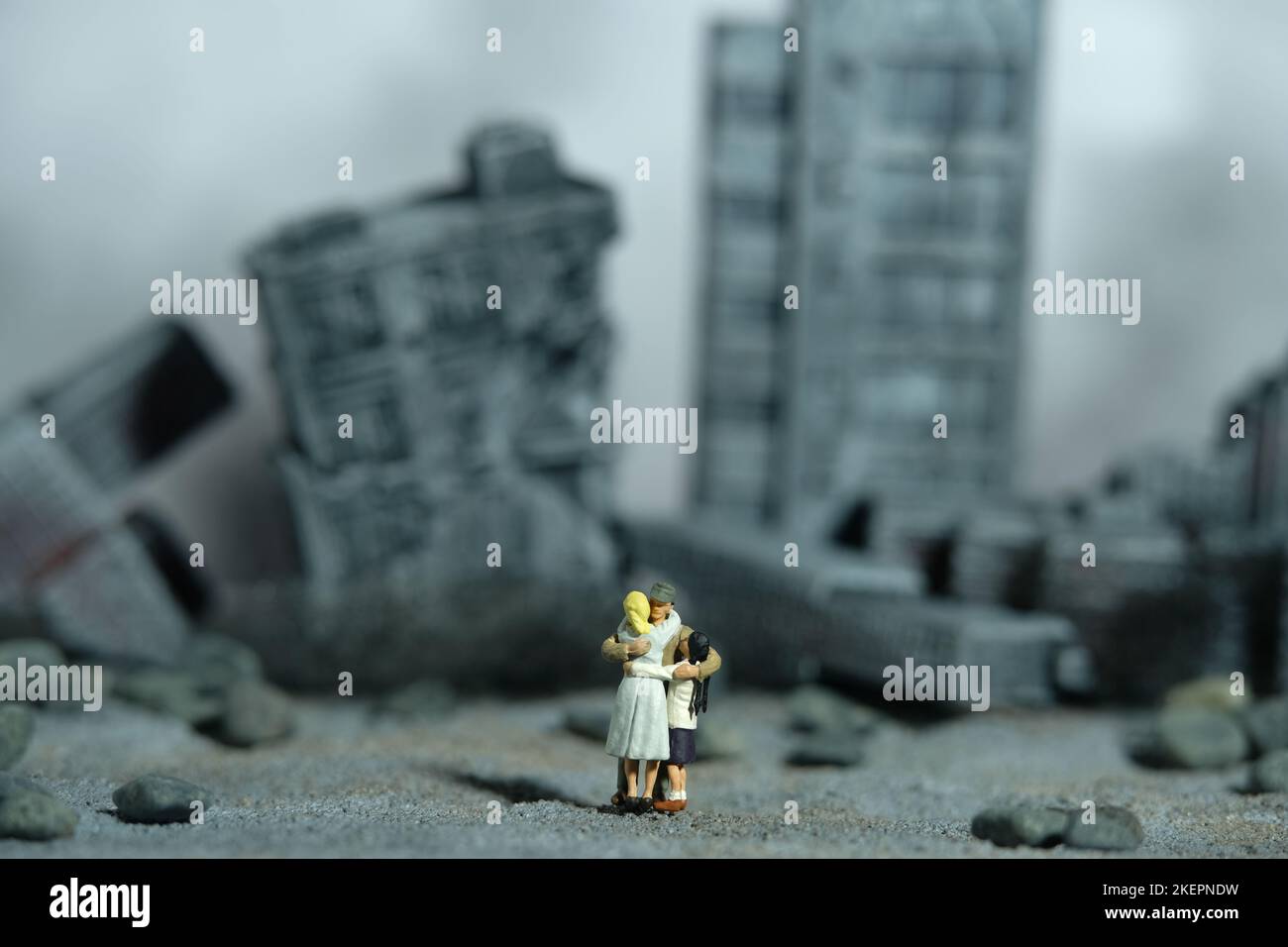 Miniatur Menschen Spielzeug Figur Fotografie. Konzept für Familientreffen. Der Vater umarmte seine Frau und seine Tochter mitten in der zerstörten Stadt. Bild pho Stockfoto