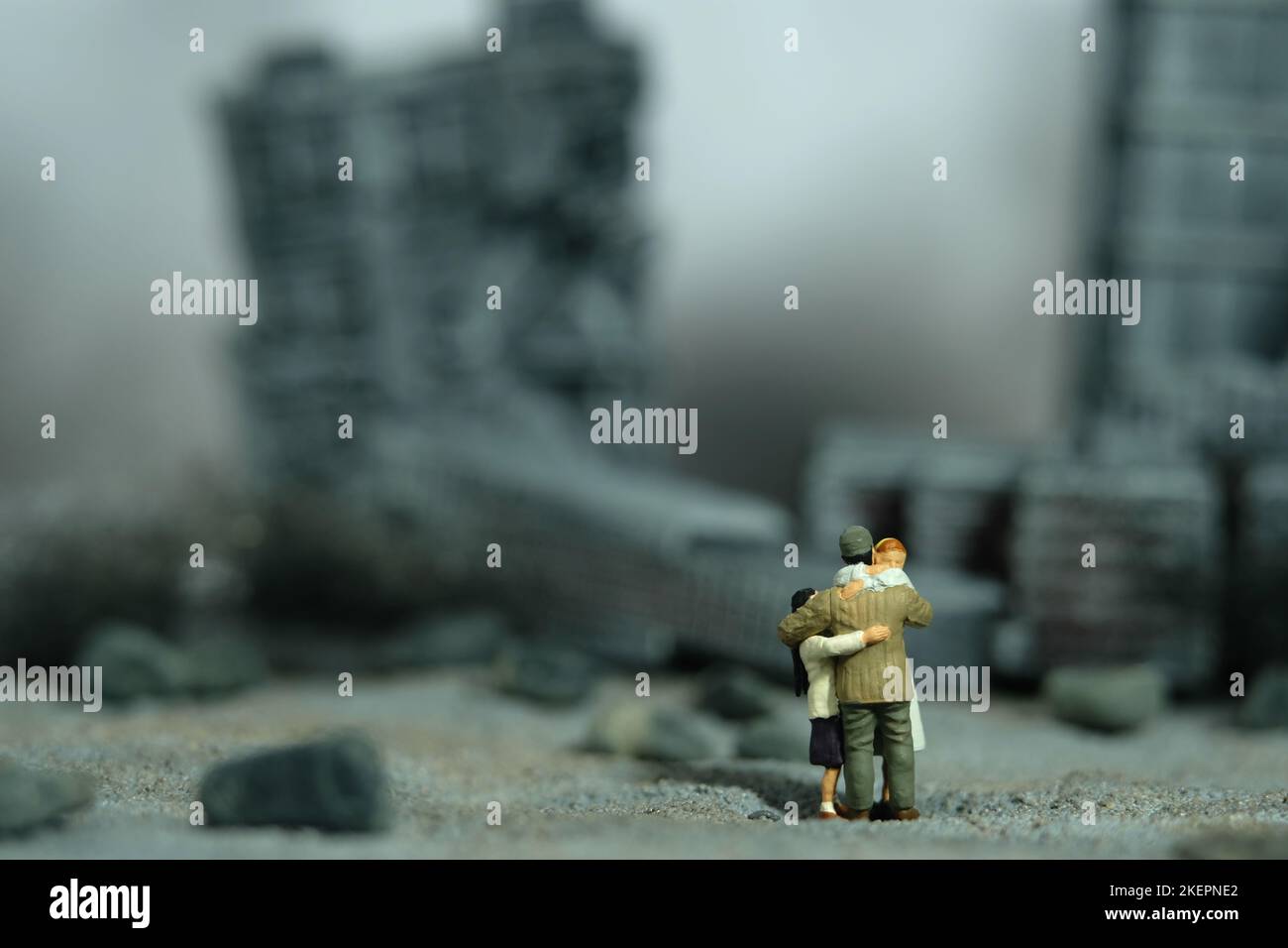 Miniatur Menschen Spielzeug Figur Fotografie. Konzept für Familientreffen. Der Vater umarmte seine Frau und seine Tochter mitten in der zerstörten Stadt. Bild pho Stockfoto