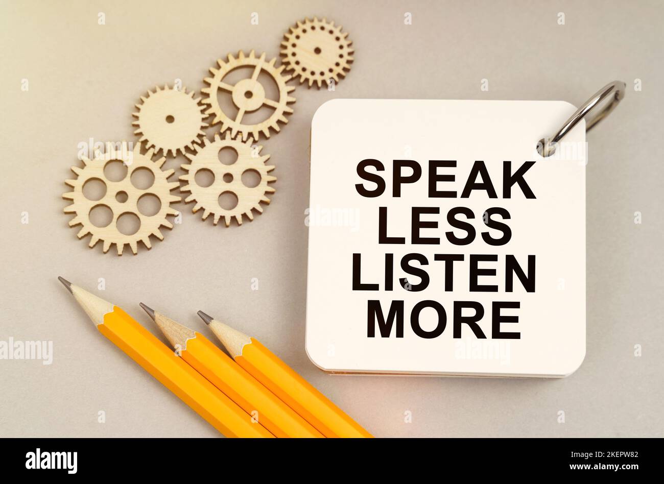 Geschäfts- und Finanzkonzept. Auf dem Tisch sind Zahnräder, Stifte und ein Notizbuch mit der Aufschrift - Speak Less Listen More Stockfoto