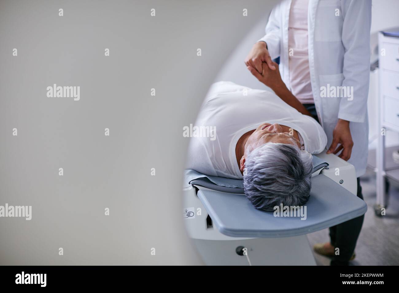 Eine ältere Frau, die zuvor von einem Arzt getröstet wurde, und eine MRT-Untersuchung. Stockfoto