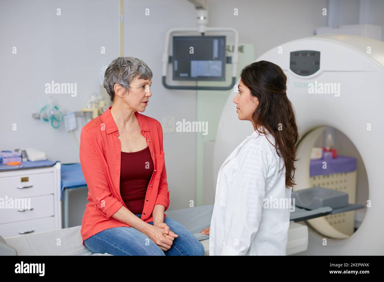 Warten nur auf die Ergebnisse jetzt. Eine reife Frau im Gespräch mit einem Arzt vor und MRI-Scan. Stockfoto