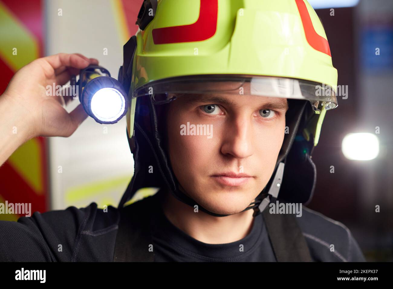 Junger Feuerwehrmann in Uniform, der vor einem Feuerwehrauto steht Stockfoto