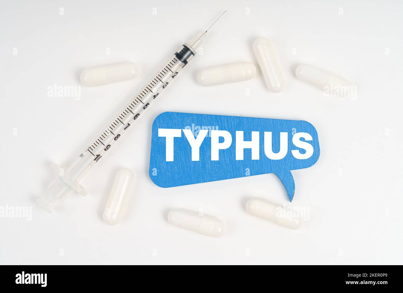 Medizin und Gesundheitskonzept. Auf weißem Hintergrund Pillen, eine Spritze und eine blaue Platte mit der Aufschrift - TYPHUS Stockfoto
