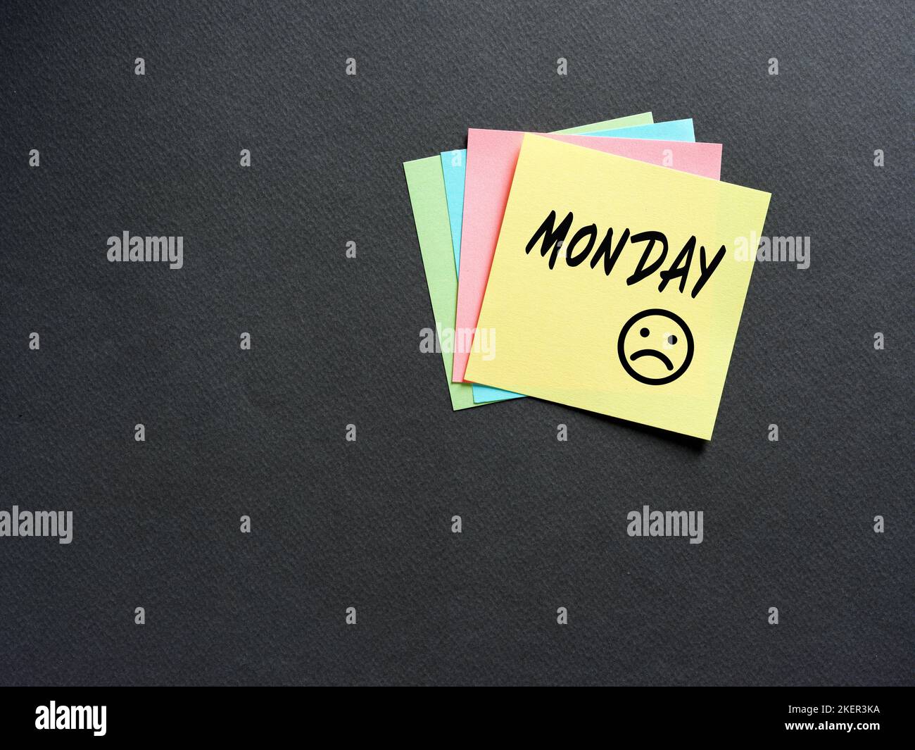 Notieren Sie sich das Papier mit dem Wort Montag mit unglücklichen Emoticons. Unglücklich, depressiv oder traurig am ersten Arbeitstag der Woche. Geschäfts- oder schulische Bildung Stockfoto