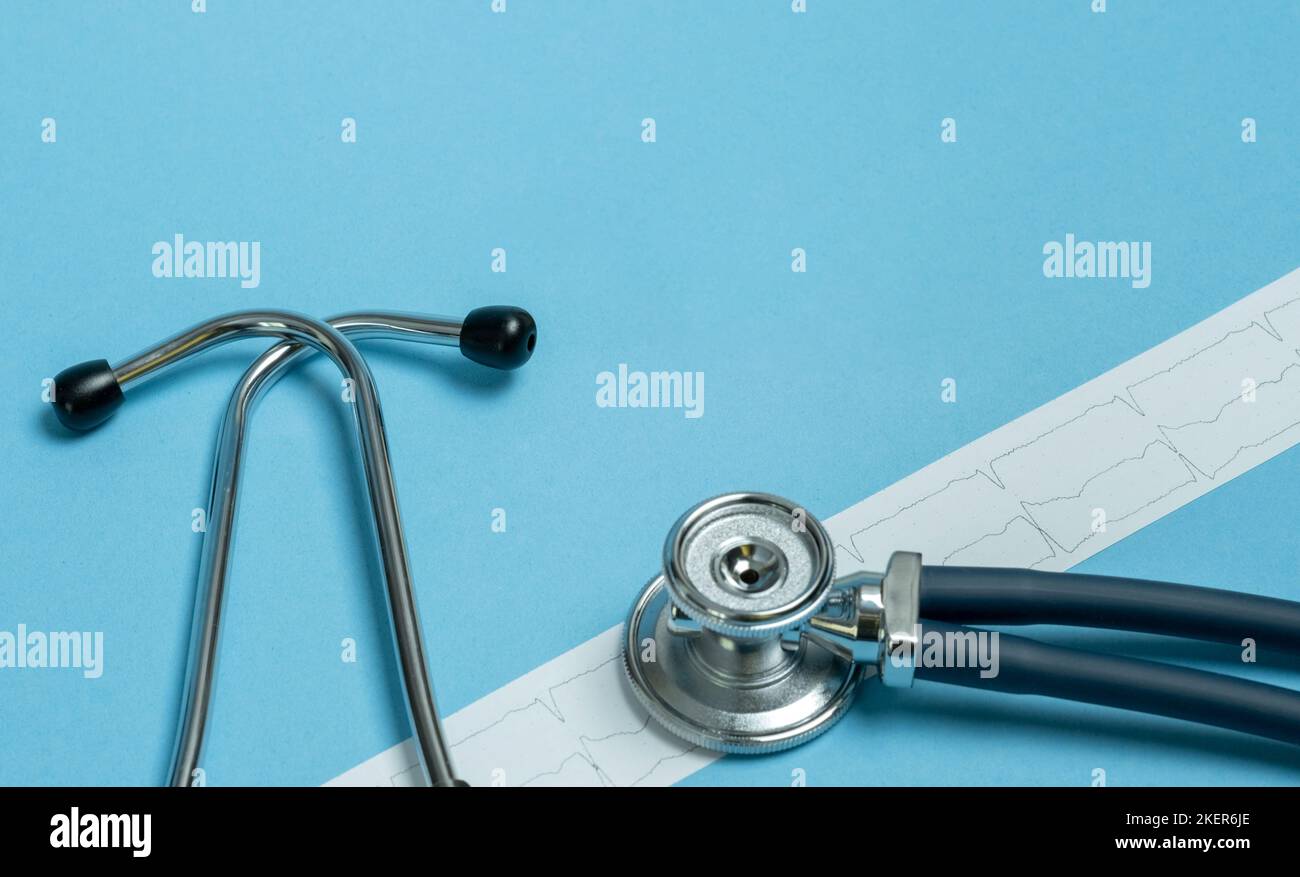 Stethoskop- und Kardiogramm-Ergebnisse auf blauem Hintergrund. Gesundheitsfürsorge und chirurgisches Konzept. Stockfoto