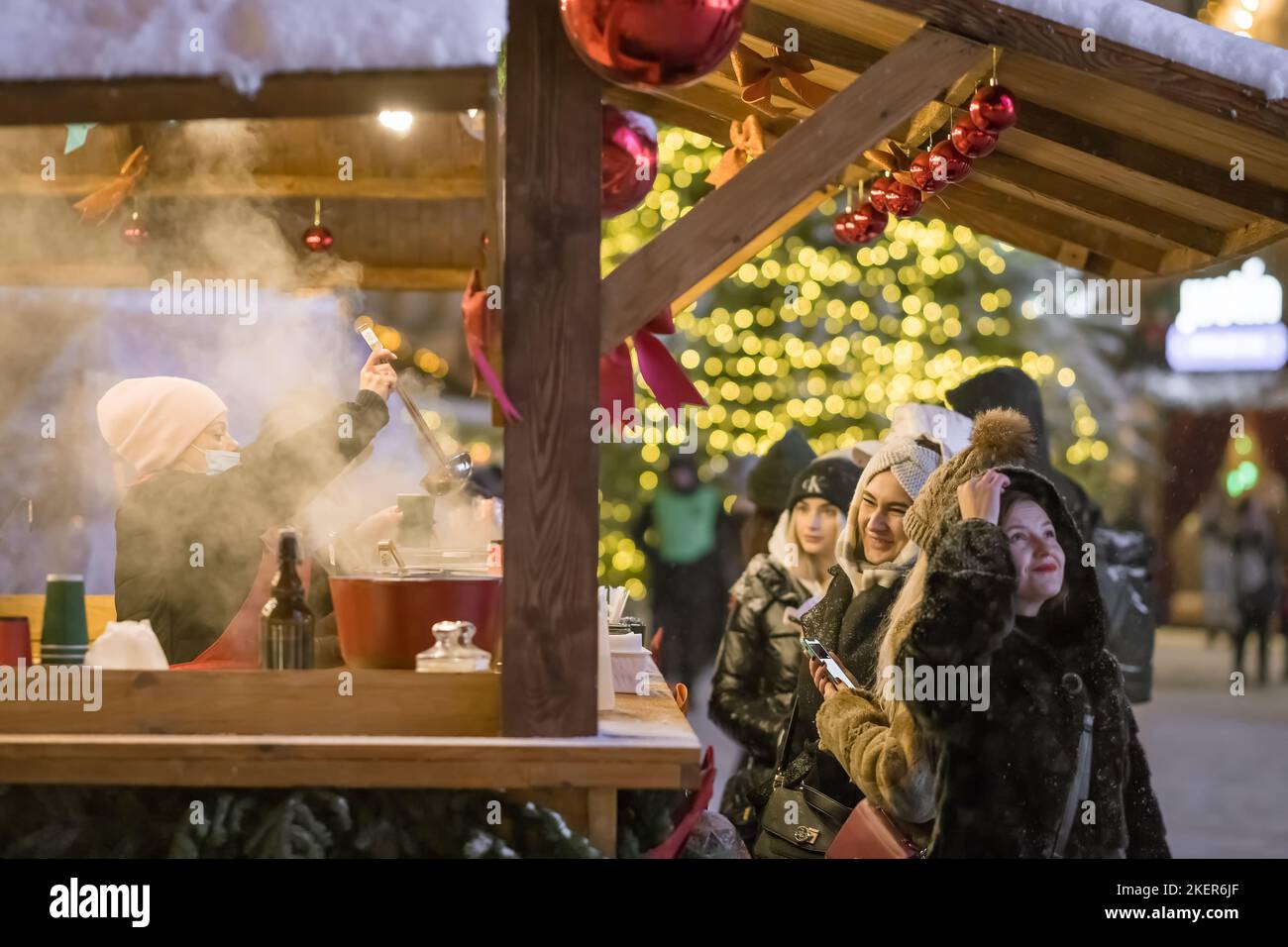 Menschen kaufen Glühwein auf dem traditionellen Weihnachtsmarkt in Kiew, Ukraine Stockfoto