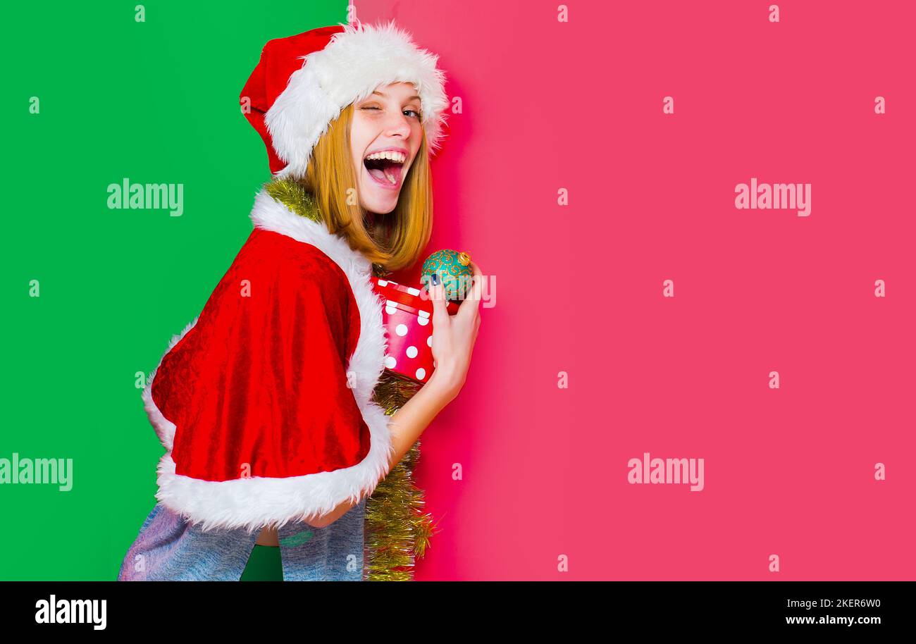 Lustige winkingh Frau mit weihnachtsball. Hübsche Dame feiern Winterferien halten weihnachtsbälle auf isolierten Hintergrund Junge schöne Mädchen mit Stockfoto