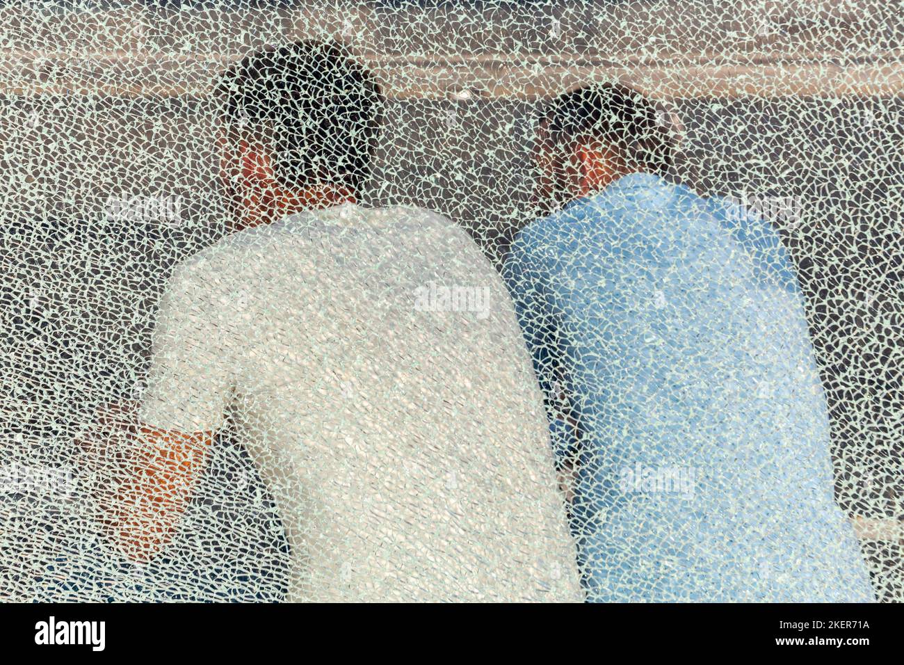 Zwei Personen saßen in einer Bushütte, gesehen durch eine kaputte Glaswand. Brüssel. Stockfoto