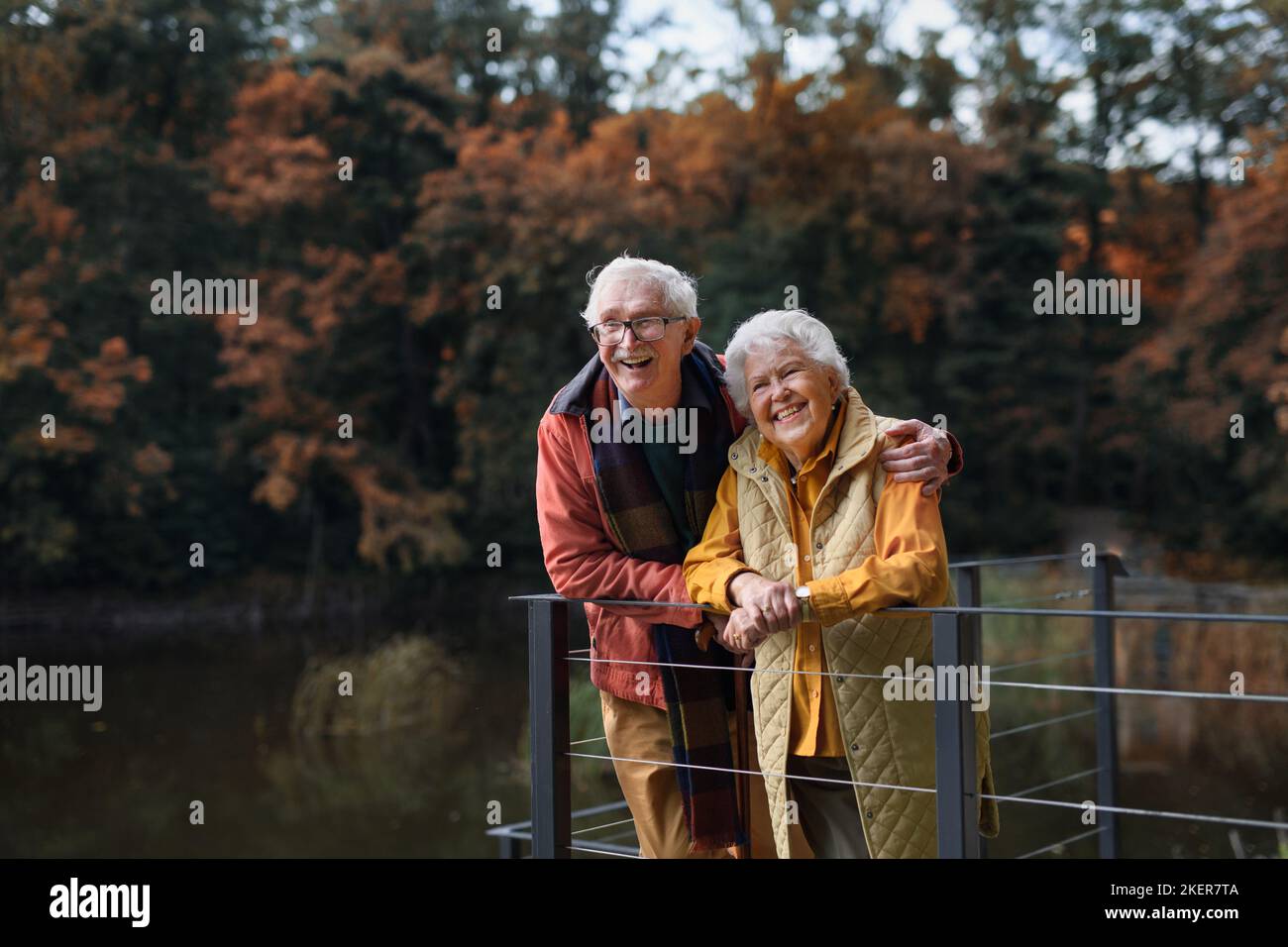 Glückliches Seniorenpaar beim Herbstspaziergang in der Nähe des Sees, Pause machen. Stockfoto