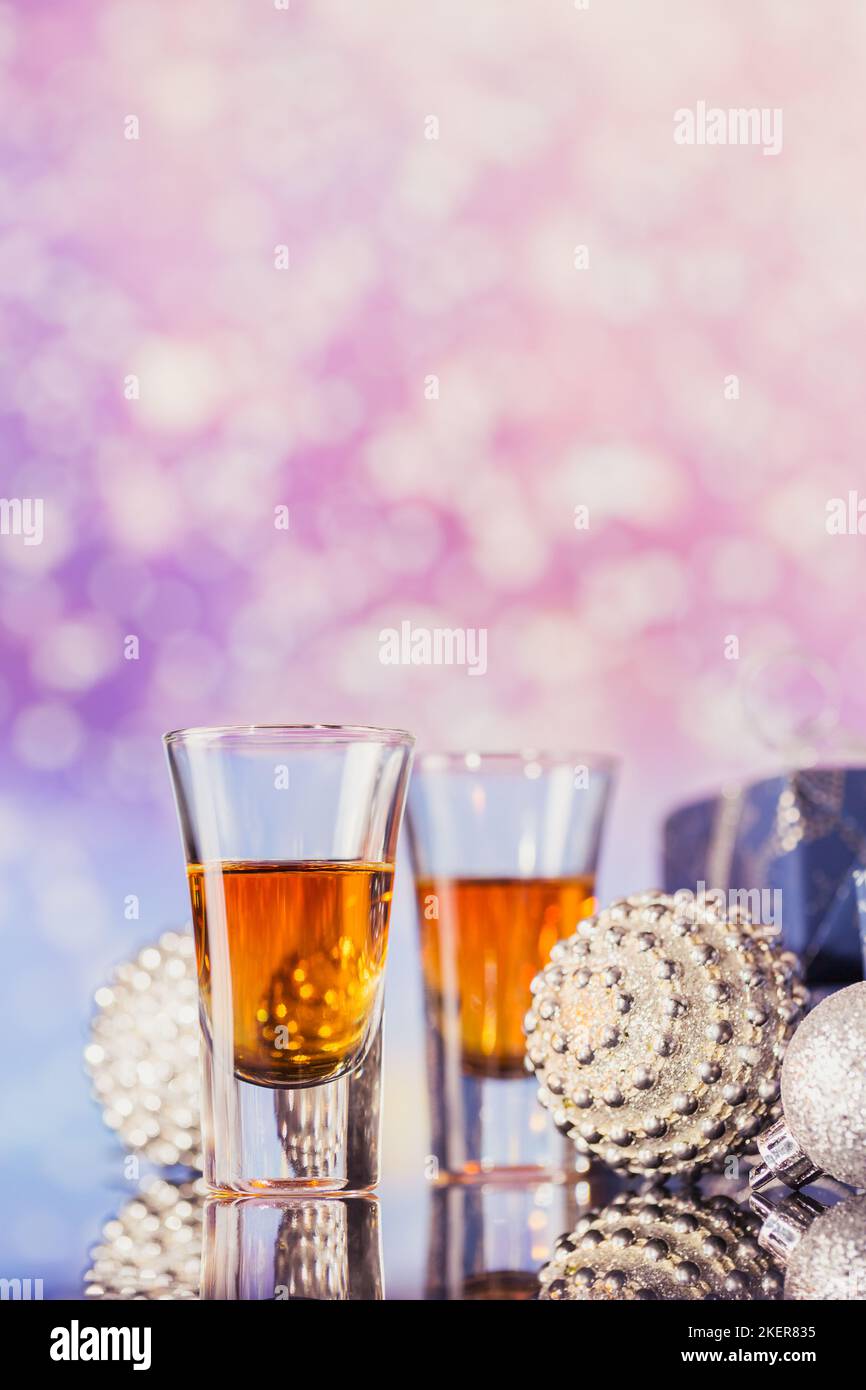 Zwei Gläser Whiskey oder Bourbon mit weihnachtlicher Dekoration auf hellem Bokeh-Hintergrund. Neujahr, Weihnachten und Winterferien Whiskey Stimmung Konzept Stockfoto