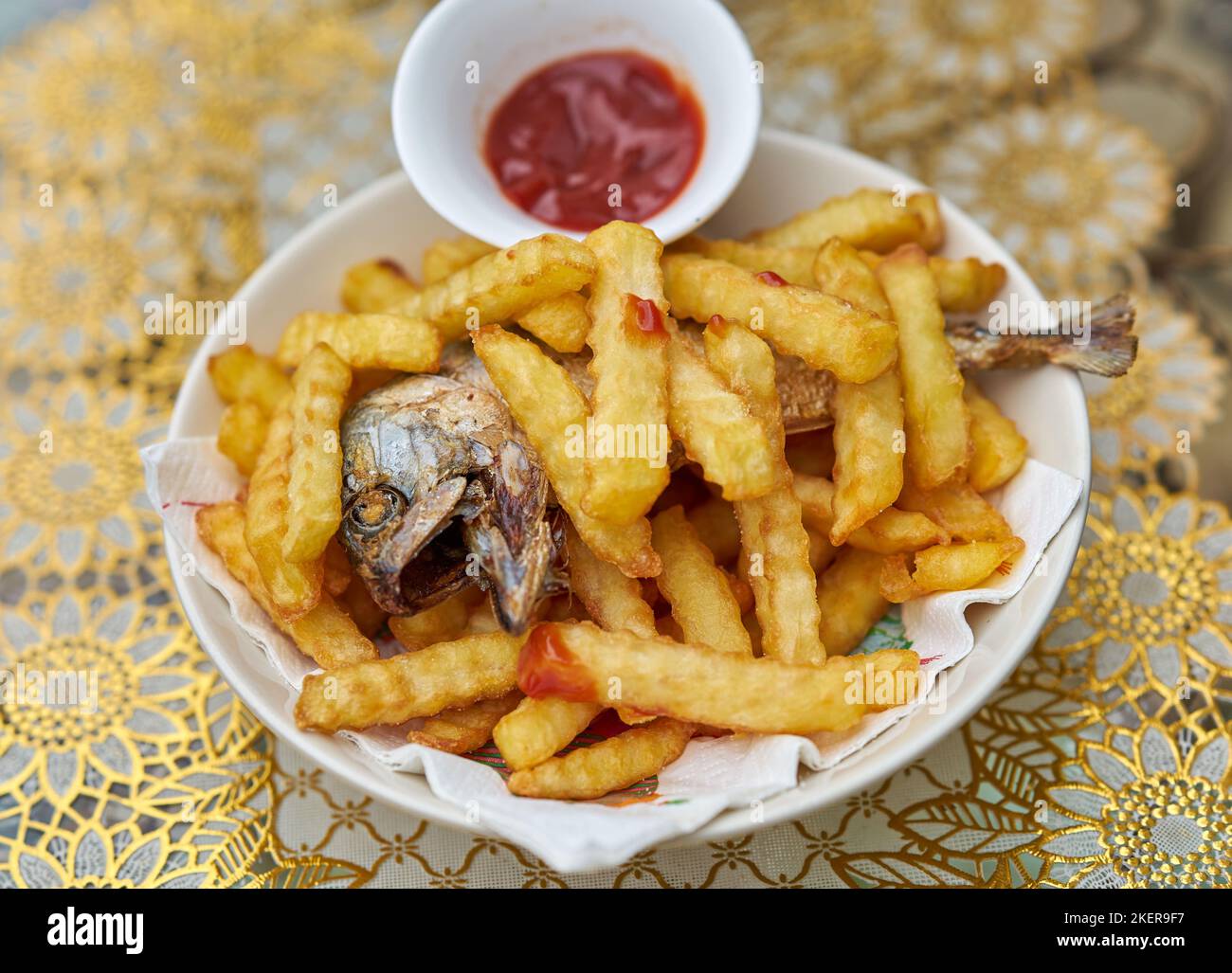 Ein Teller mit Fisch und Chips mit Tomatenketchup. Stockfoto