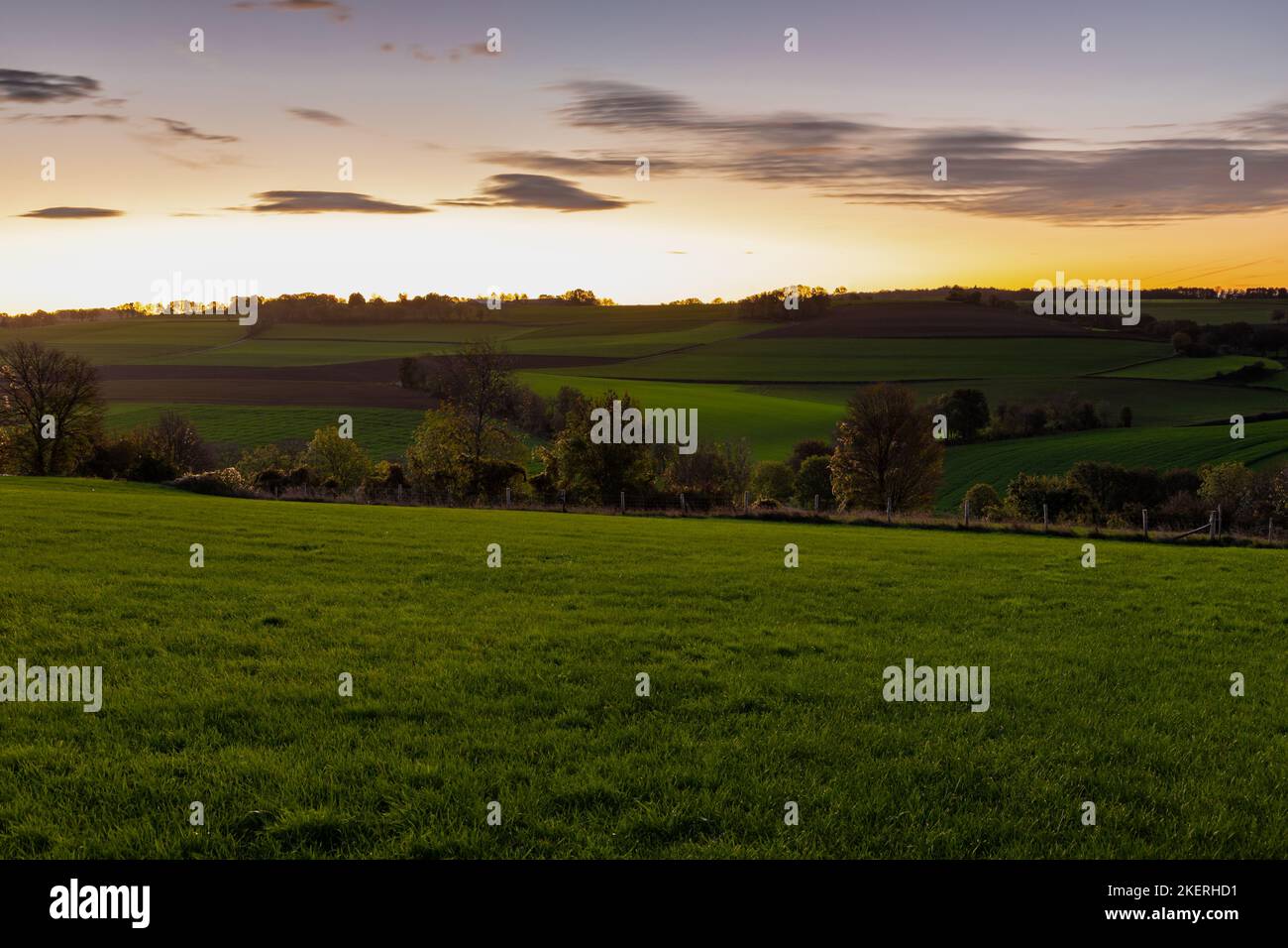 Spektakulärer und farbenfroher Sonnenaufgang über einer hügeligen Landschaft mit kurvigen Straßen und landwirtschaftlichen Feldern im Süden von Limburg. Toskanische Landschaft Stockfoto