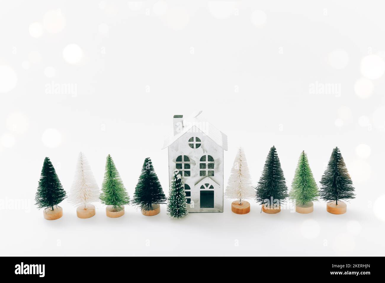 Weihnachtsdekoration, Urlaubskonzept. Miniaturhaus und Tannen auf weißem Hintergrund. Stockfoto