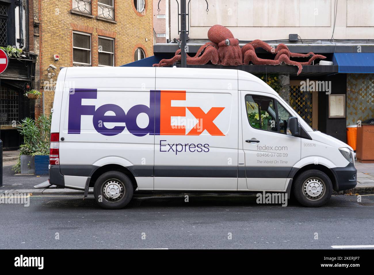 FedEx Lieferwagen liefert ein Paket in London, Großbritannien. Konzept: Kurierdienste, Paketzustellung, Expressversand, Online-Bestellung Stockfoto