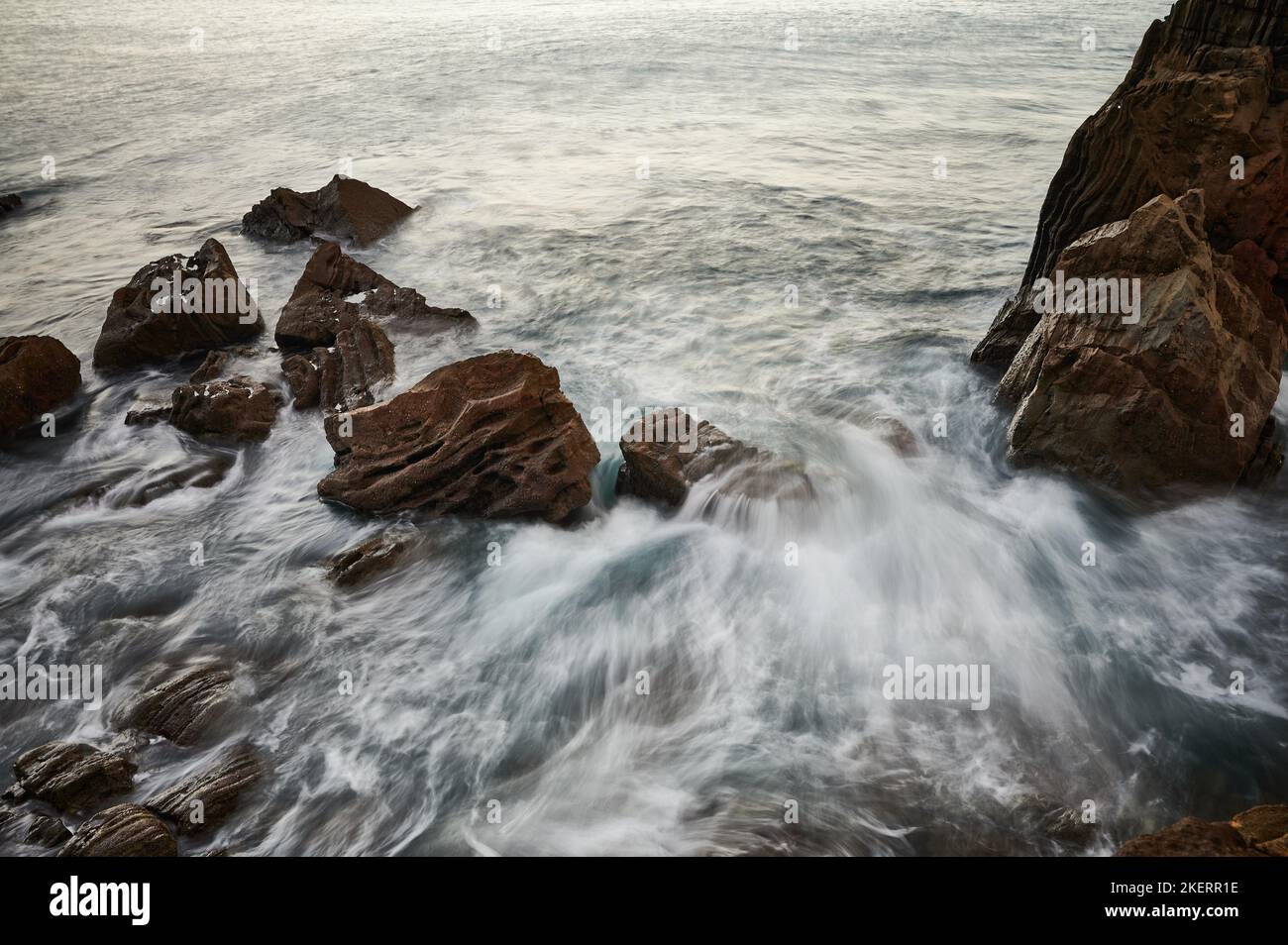 Wellen brechen auf den Felsen mit Langzeitbelichtung Bild Stockfoto