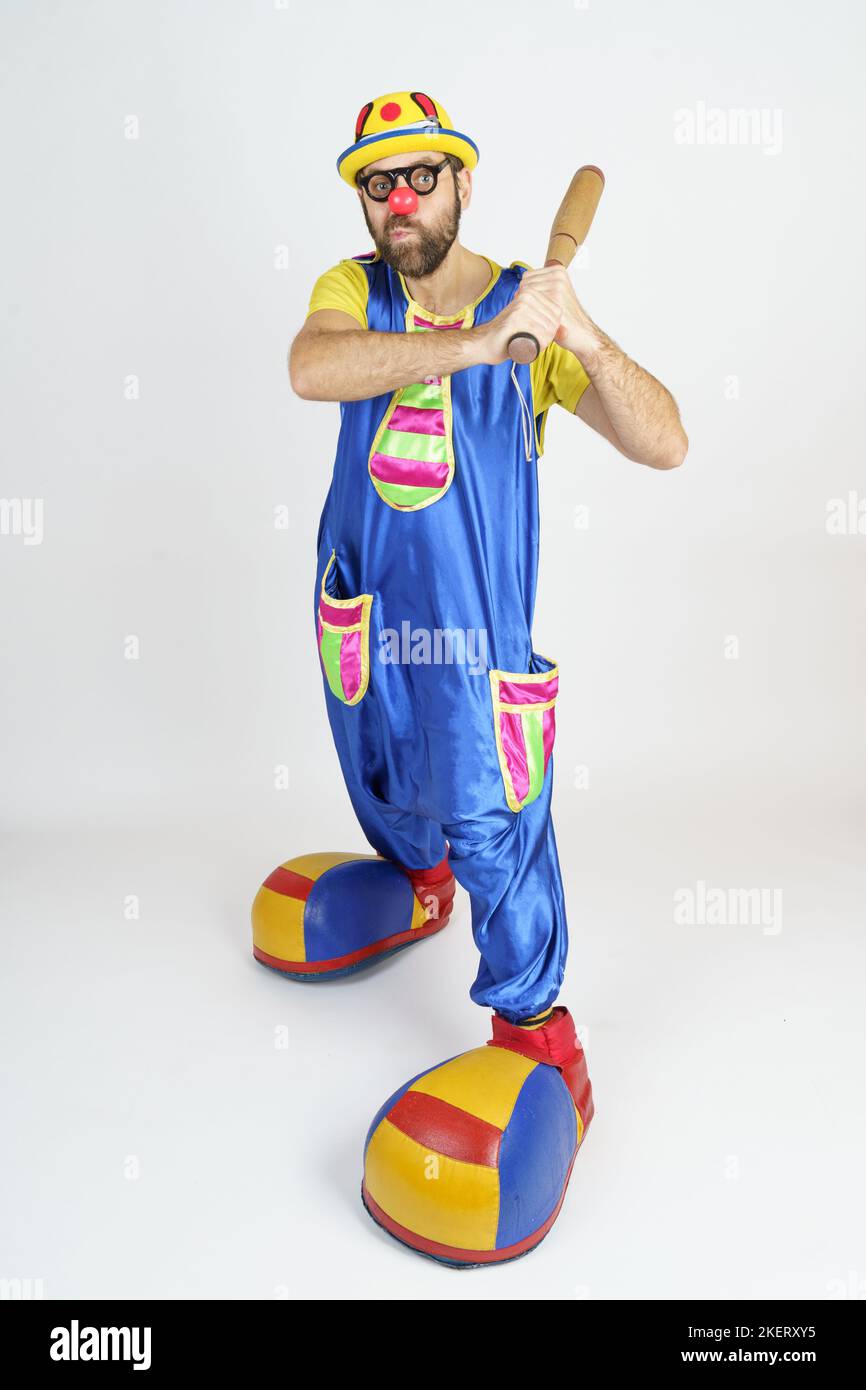 Urlaubskonzept. Der Clown ist ein Mann in einem leuchtend blauen und gelben Anzug mit einem Baseballschläger. Stockfoto