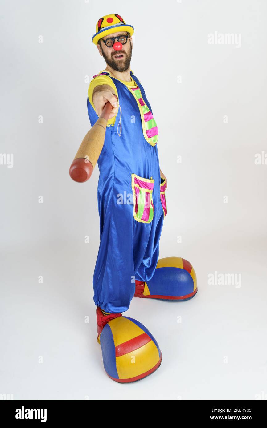 Urlaubskonzept. Der Clown ist ein Mann in einem leuchtend blauen und gelben Anzug mit einem Baseballschläger. Stockfoto