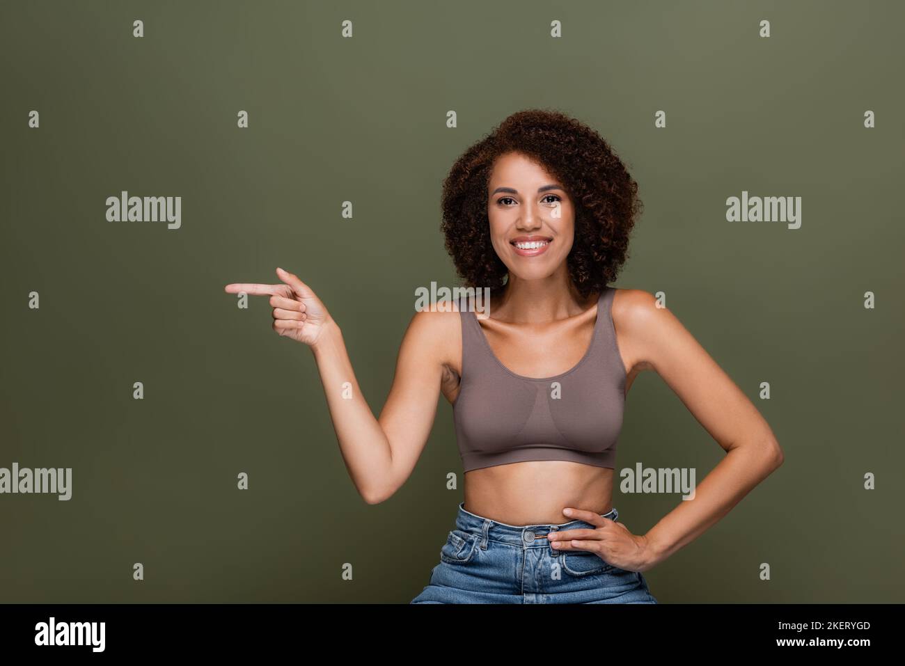 Lächelndes afroamerikanisches Modell oben zeigt mit Finger isoliert auf grünem, stockem Bild Stockfoto