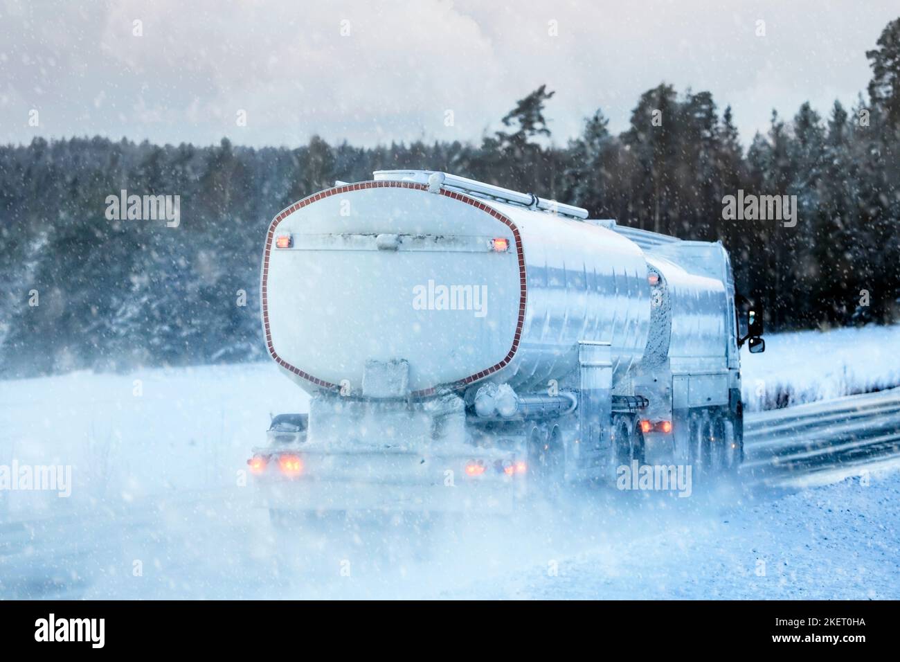 Rückansicht eines Tankers, der an einem Wintertag bei starkem Schneefall die Autobahn entlang fährt. Stockfoto