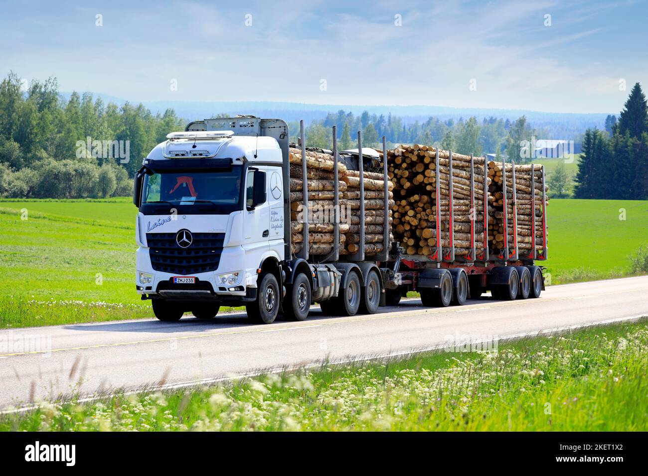 Weißer Mercedes-Benz Arocs 3768 Holzfäller R Laine Oy liefert an einem schönen Sommertag Holzladung auf der Route E63 aus. Jamsa, Finnland. 6. Juni 2019. Stockfoto