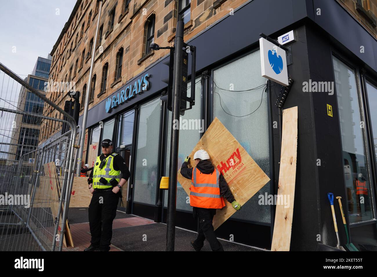 Arbeiter reparieren Fenster in der Niederlassung von Barclays Clyde Place Quay in Glasgow, nachdem sie von Mitgliedern des Extinction Rebellion Scotland zerbrochen wurden, da sie verlangen, dass Barclays seine Verbindungen zu fossilen Brennstofffirmen abschneidet. Der Protest ist Teil der „Extinction Rebellion“- und „Money Rebellion“-Kampagne „Better Without Barclays“ im Vereinigten Königreich. Bilddatum: Montag, 14. November 2022. Stockfoto