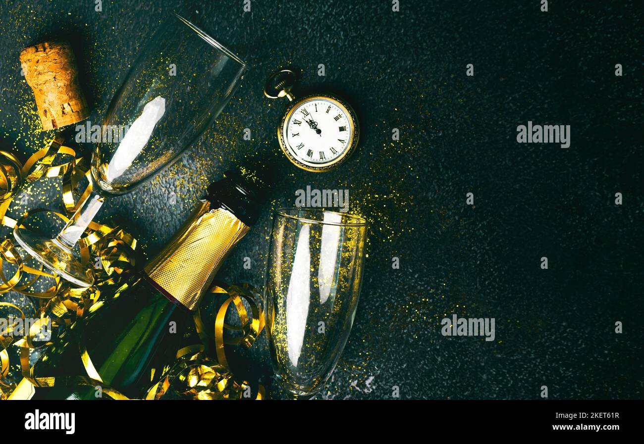 Frohes neues Jahr. Champagnerflasche mit zwei Gläsern, goldenen Luftschlangen, funkelndem Glitzer und antiker Uhr mit Kopierraum über grunge Hintergrund. Neu Ja Stockfoto