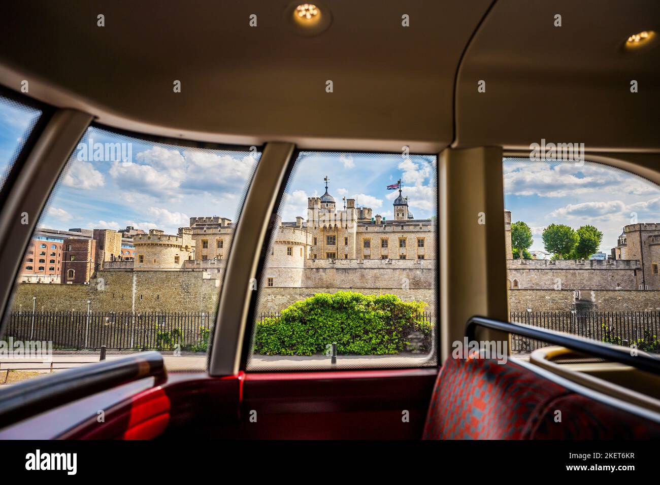 Ein routemaster Red London Bus blickt auf den Tower von london.das Bild wurde durch die Fenster des Busses aufgenommen und zeigt den Tower mit Union Jack Flack Stockfoto