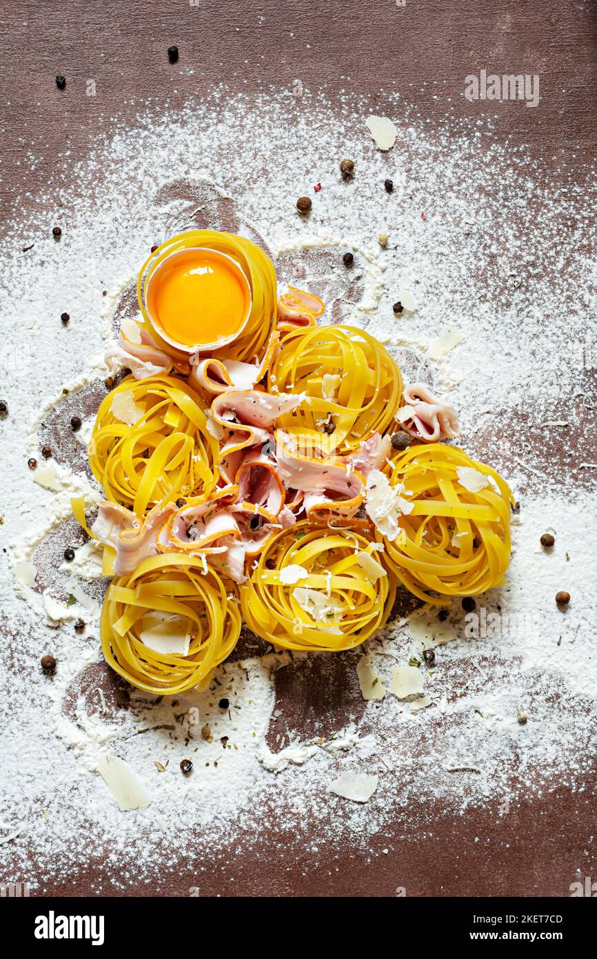 Rohe gelbe italienische Pasta (Nester) Pappardelle, Fettuccine oder Tagliatelle in Form eines Weihnachtsbaums auf braunem Hintergrund, Nahaufnahme. Ei hausgemacht Stockfoto