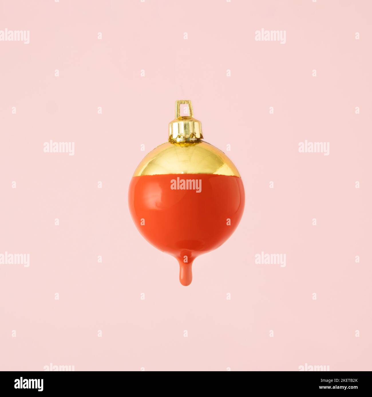 Goldene Weihnachtskugel Dekoration mit roter Farbe tropfend. Minimales Neujahrskonzept. Stockfoto