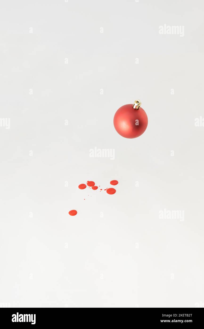 Rote Weihnachtskugel mit roten Farbtropfen auf weißem Backgorund. Minimales Neujahrskonzept. Stockfoto
