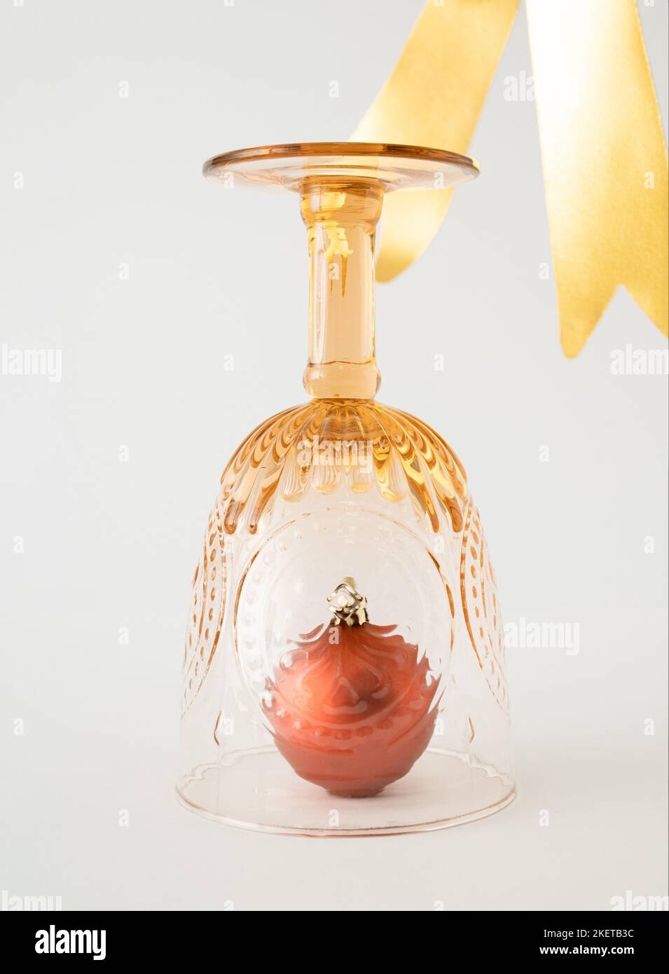 Weihnachtskugeldekoration in Vintage Trinkglas und goldenem Band auf weißem Hintergrund. Minimales Neujahrskonzept. Stockfoto