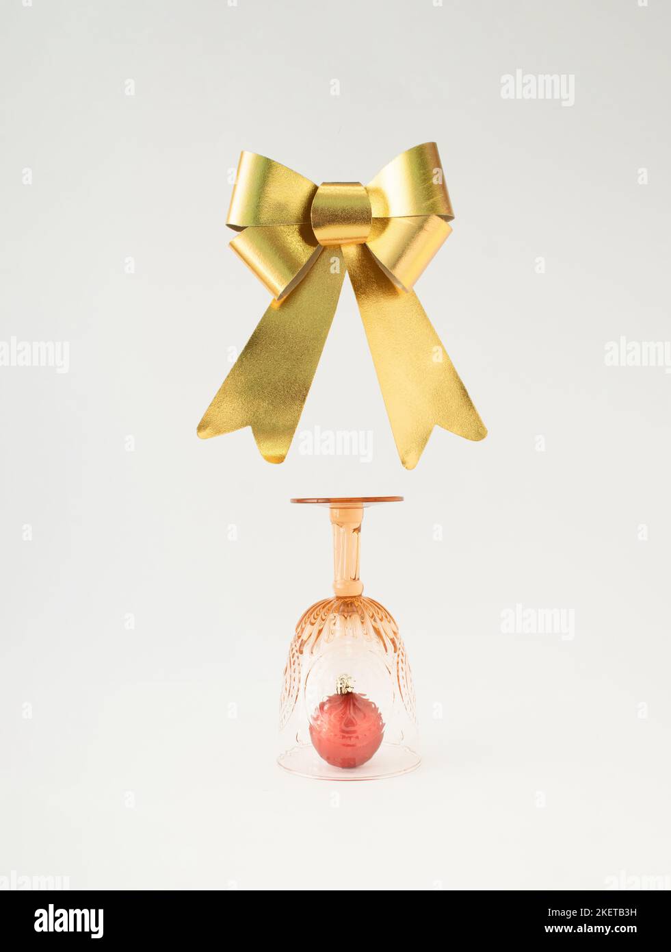 Weihnachtskugel aus Vintage-Trinkglas und goldenem Band auf weißem Hintergrund. Minimales Neujahrskonzept. Stockfoto