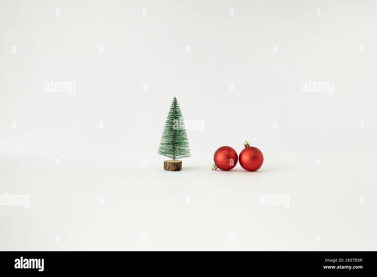 Weihnachtsbaum und zwei rote Kugeln auf weißem Hintergrund. Minimales Neujahrskonzept. Stockfoto