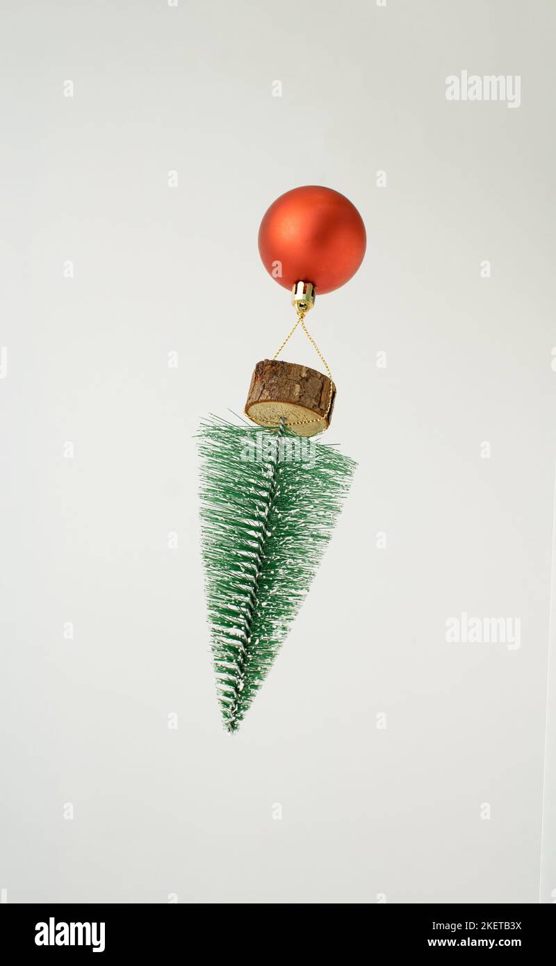 Heißluftballon aus roter Weihnachtskugel und Baum, der vor weißem Hintergrund fliegt. Minimales Neujahrskonzept. Stockfoto