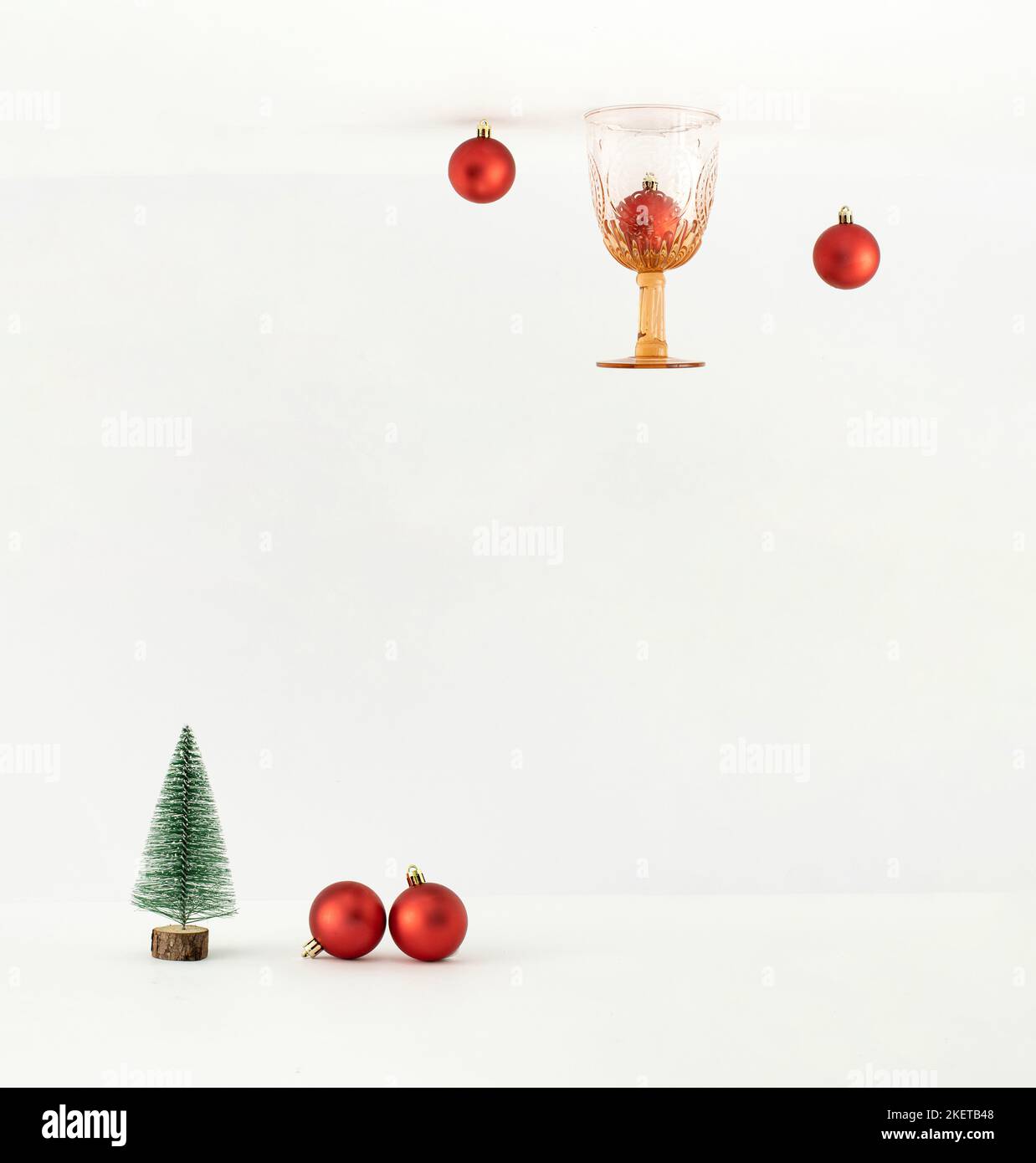 Umgekehrte Perspektive mit Weihnachtskugeln, Vintage-Trinkglas und Baum auf weißem Hintergrund. Minimales Neujahrskonzept. Stockfoto
