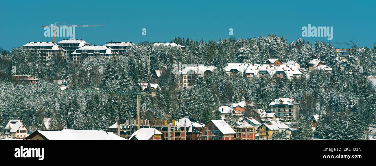Bauindustrie Wohnung und Wohnungsbau in Zlatibor in der Wintersaison unter Schnee, Gebäude und Kraniche übernehmen die Kiefernwälder Land Stockfoto