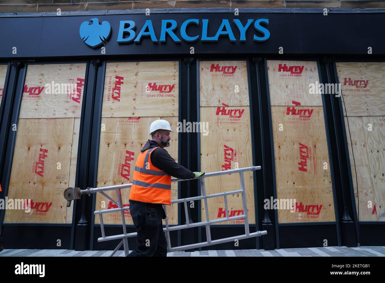 Arbeiter reparieren Fenster in der Niederlassung von Barclays Clyde Place Quay in Glasgow, nachdem sie von Mitgliedern des Extinction Rebellion Scotland zerbrochen wurden, da sie verlangen, dass Barclays seine Verbindungen zu fossilen Brennstofffirmen abschneidet. Der Protest ist Teil der „Extinction Rebellion“- und „Money Rebellion“-Kampagne „Better Without Barclays“ im Vereinigten Königreich. Bilddatum: Montag, 14. November 2022. Stockfoto