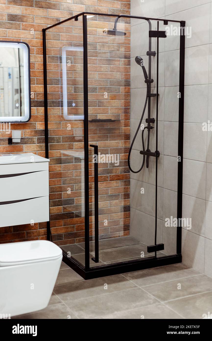 Einfaches Badezimmer mit Glaswand, schwarzer Dusche und Wandtoilette Stockfoto