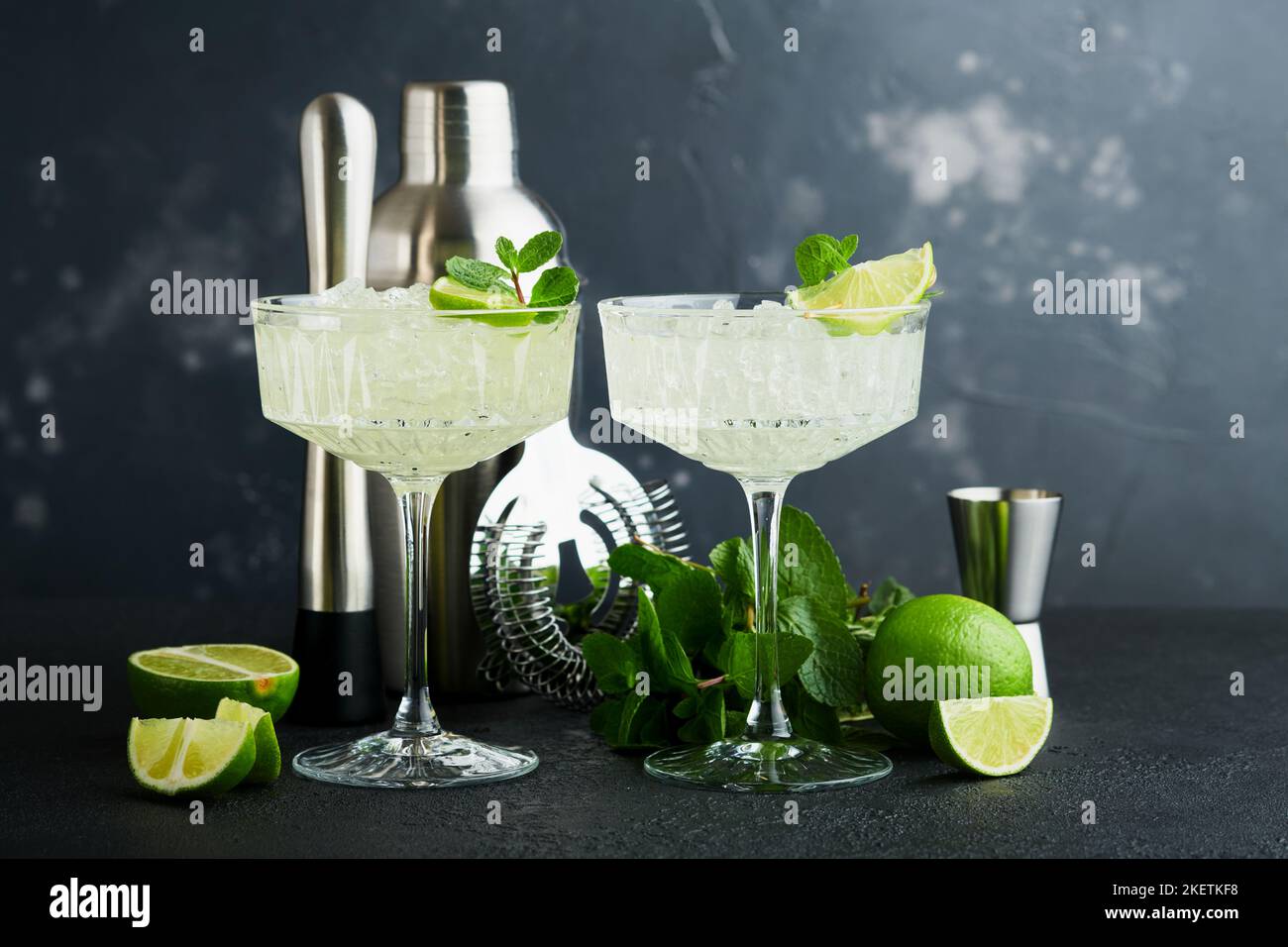 Margarita Cocktail mit Limette, Tequila, Minze und Eis auf dunklem Tisch mit erstaunlicher Hintergrundbeleuchtung, Kopierraum. Klassischer Margarita- oder Daiquiry-Cocktail. Barkarte Stockfoto