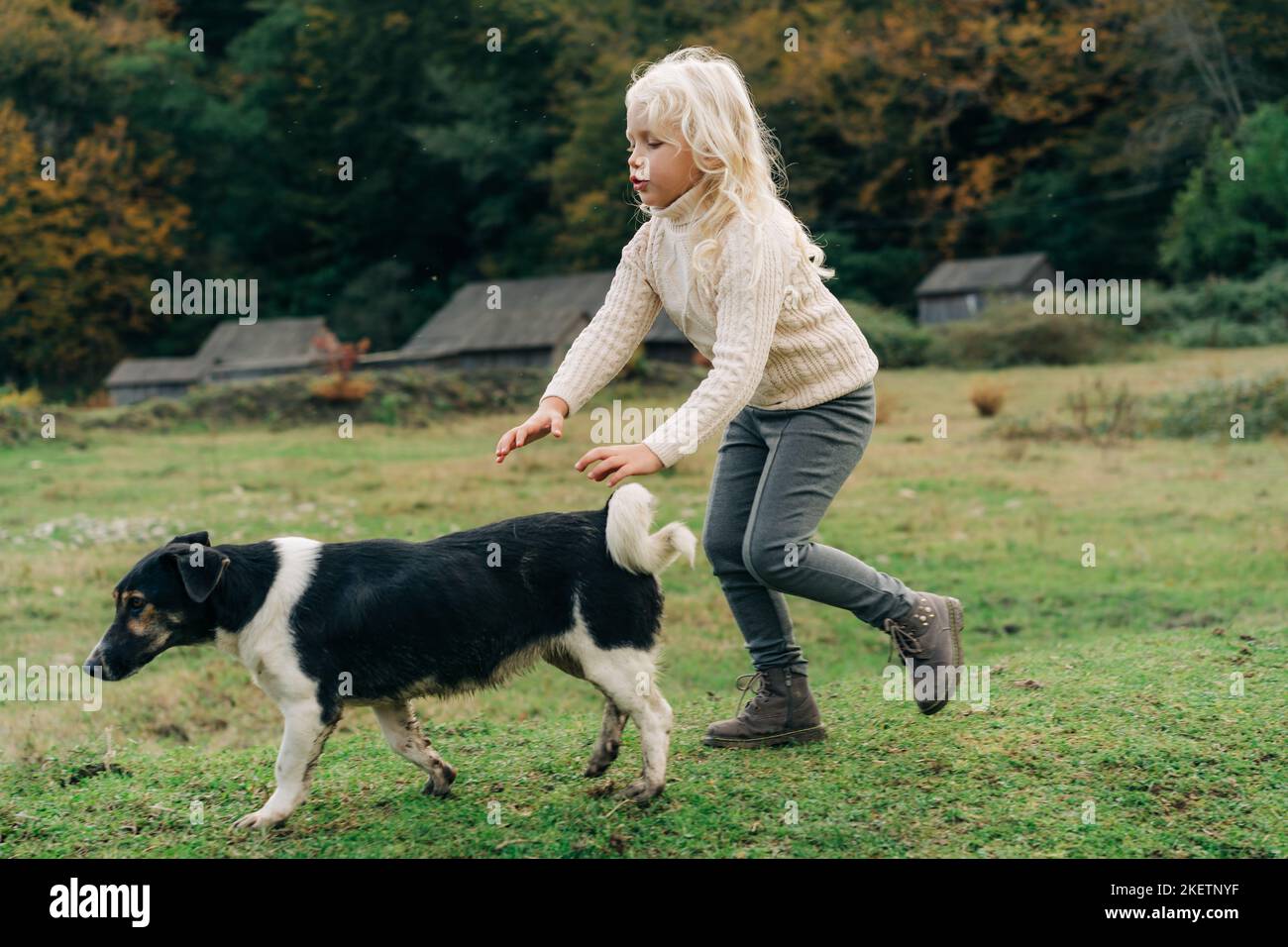 Kleines Mädchen, das mit ihrem Hund im Dorf herumläuft. Stockfoto