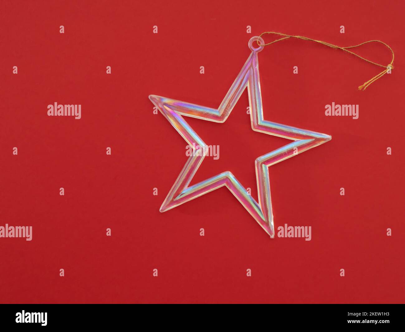 Schillernder Stern Weihnachtsdekoration auf rotem Hintergrund mit Copyspace. Stockfoto