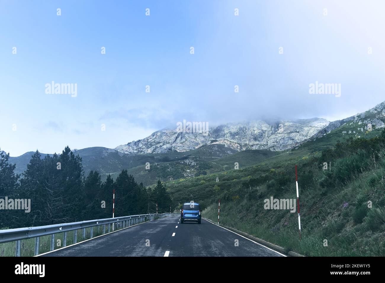 Kleiner blauer Van, der auf der einsamen Straße entlang fährt, die zu den beeindruckenden felsigen Bergen führt, ruta del Cares asturias, spanien Stockfoto